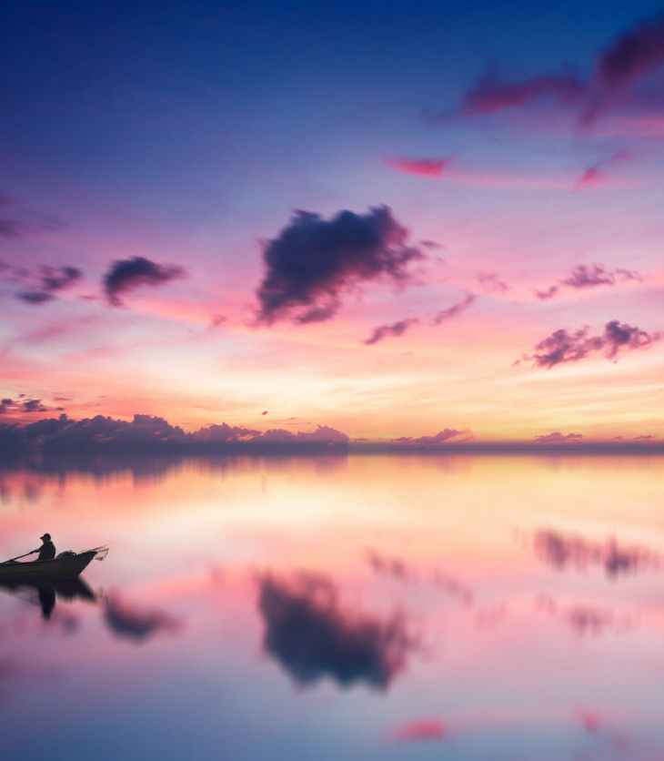 two person on boat in body of water during golden hour